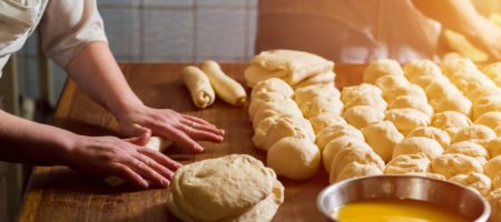 A baker rolling bread made from scratch