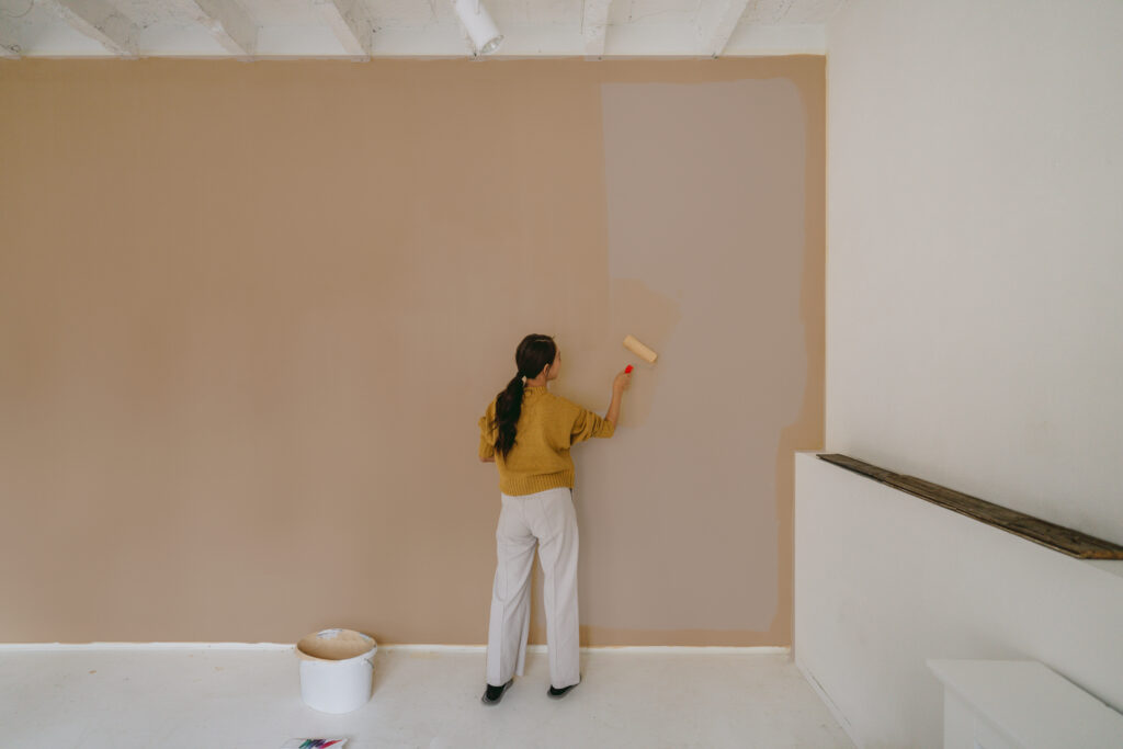 Photo of a woman painting a wall in her living room, all by herself