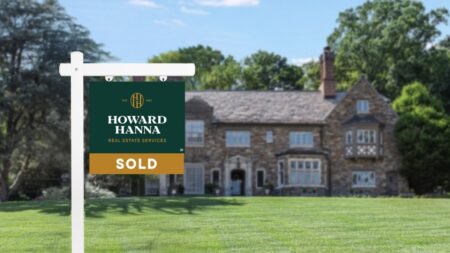 A for-sale yard sign with Howard Hanna's new logo in front of a residential home