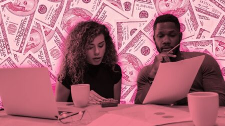 A picture of a man and a woman with their computers and spreadsheets all over the table to the backdrop of money to illustrate brokerage budget planning.