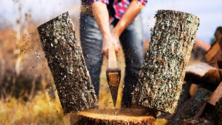 Person cutting piece of wood in half with axe