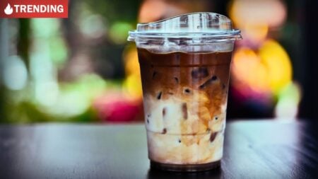 A clear plastic cup of iced coffee with a straw representing the ice coffee debate.