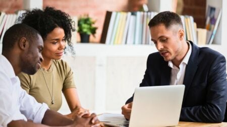 Real estate agent discusses Zillow Preview RealScout listings with buyers on a laptop