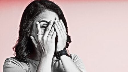 A woman with her hands over her face, peeking through the fingers to represent cringeworthy home staging practices